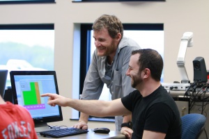 A professional photograph of a student and professor working in a Programmable Logic Controllers classroom.