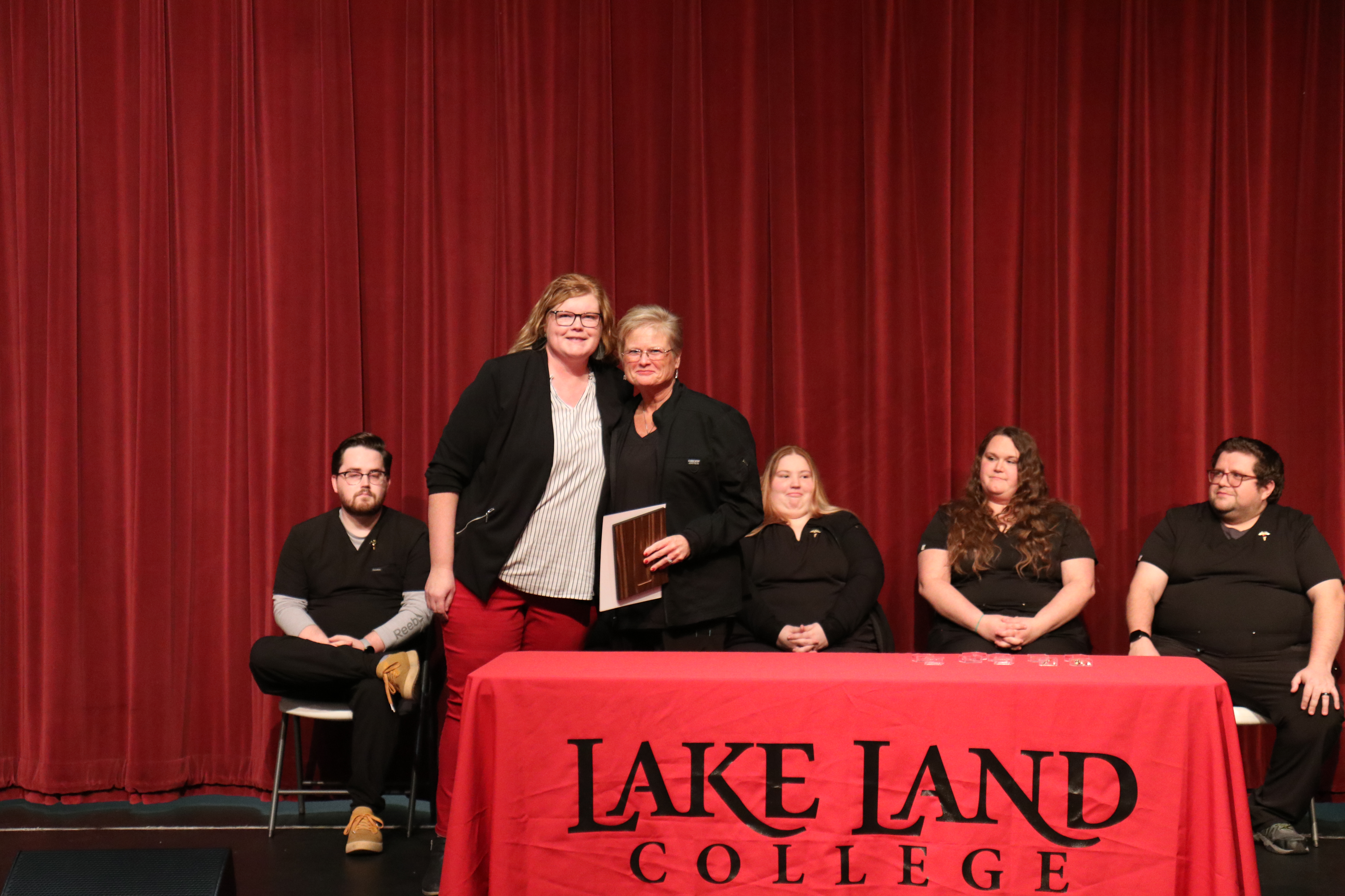 Medical Assistant Instructor presents an award to a graduating student during a ceremony. 