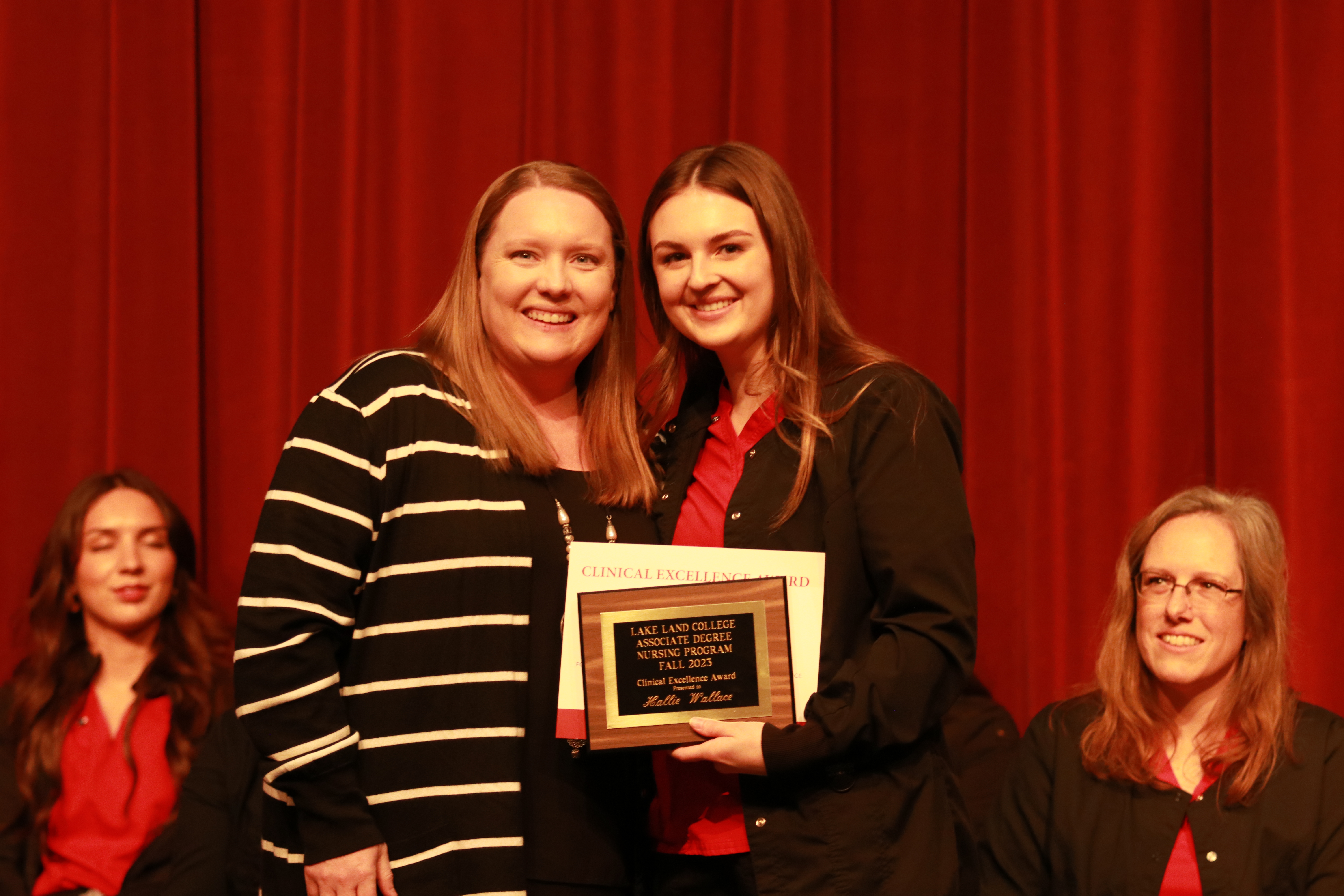 A nursing instructor presents an award to a graduating student at a ceremony. 