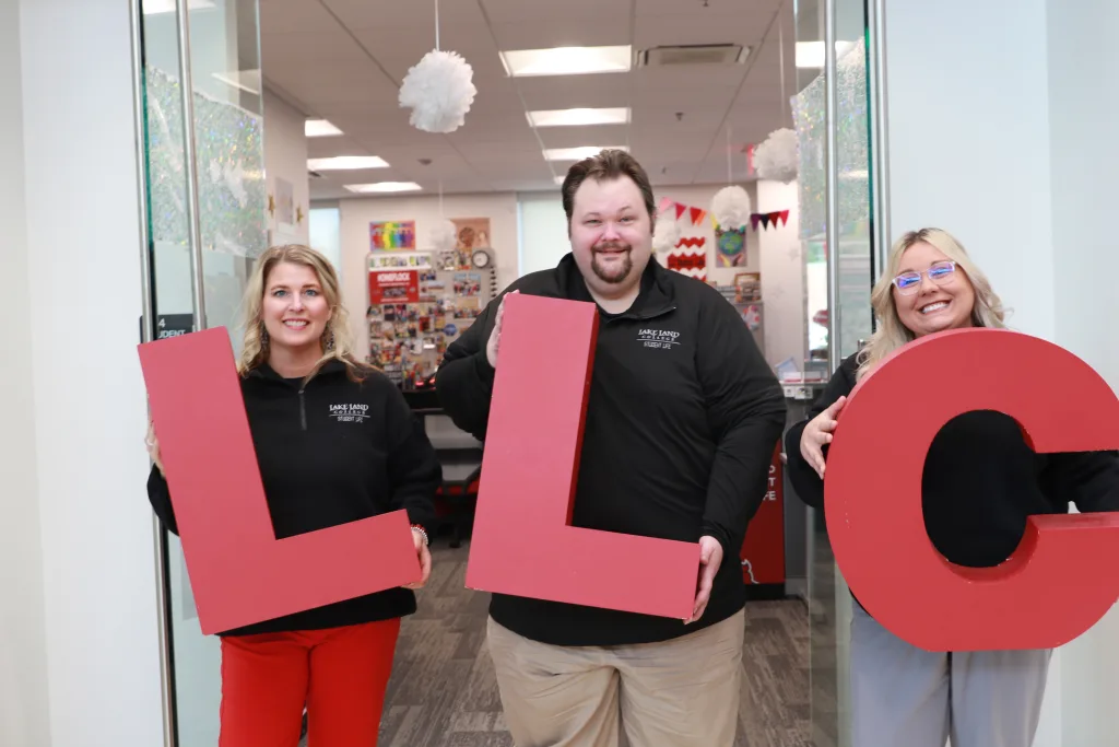 Three people holding the letter L L C