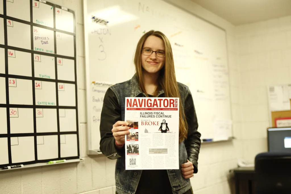 Student holding a flyer for Navigator News