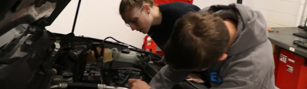Two students working on car engine