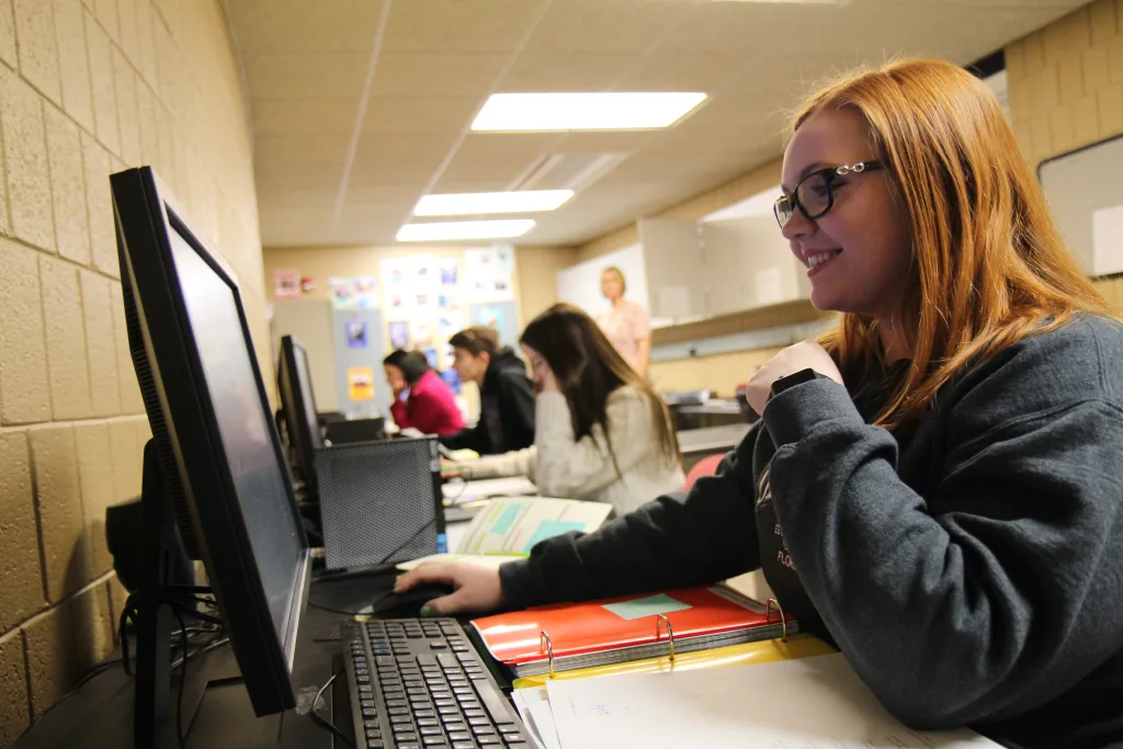 Student smiling as they look at a computer screen
