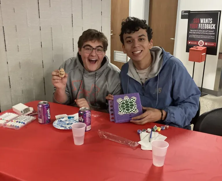 Two students smiling and showing their crafts