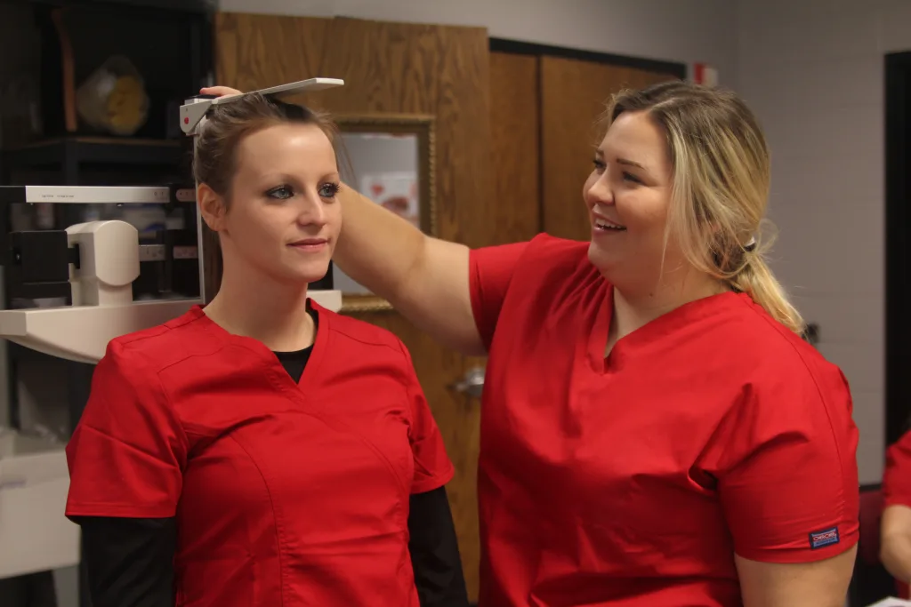 Student nurse taking another student's height