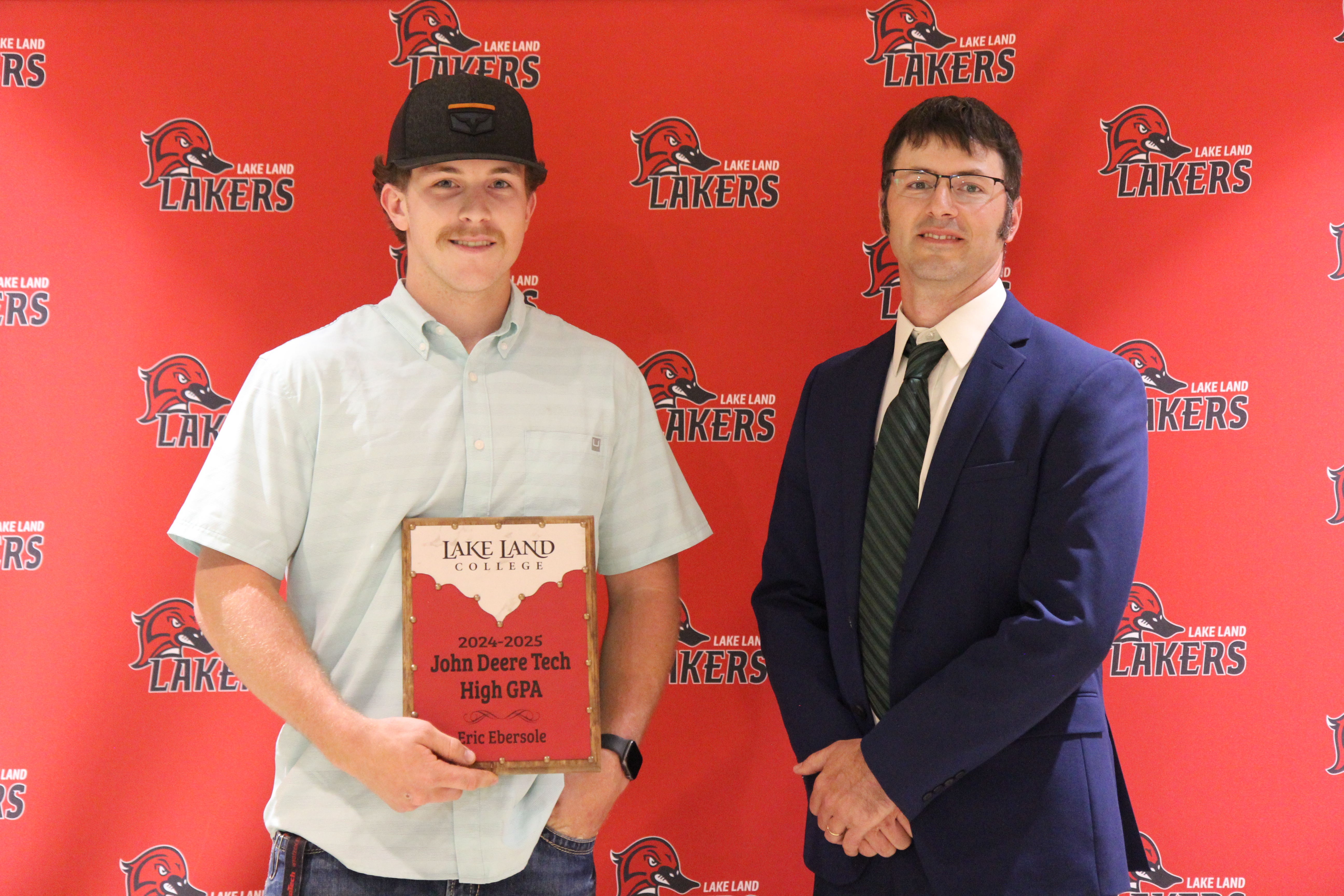 A Lake Land College John Deere Tech instructor presenting an award to a graduating student. 