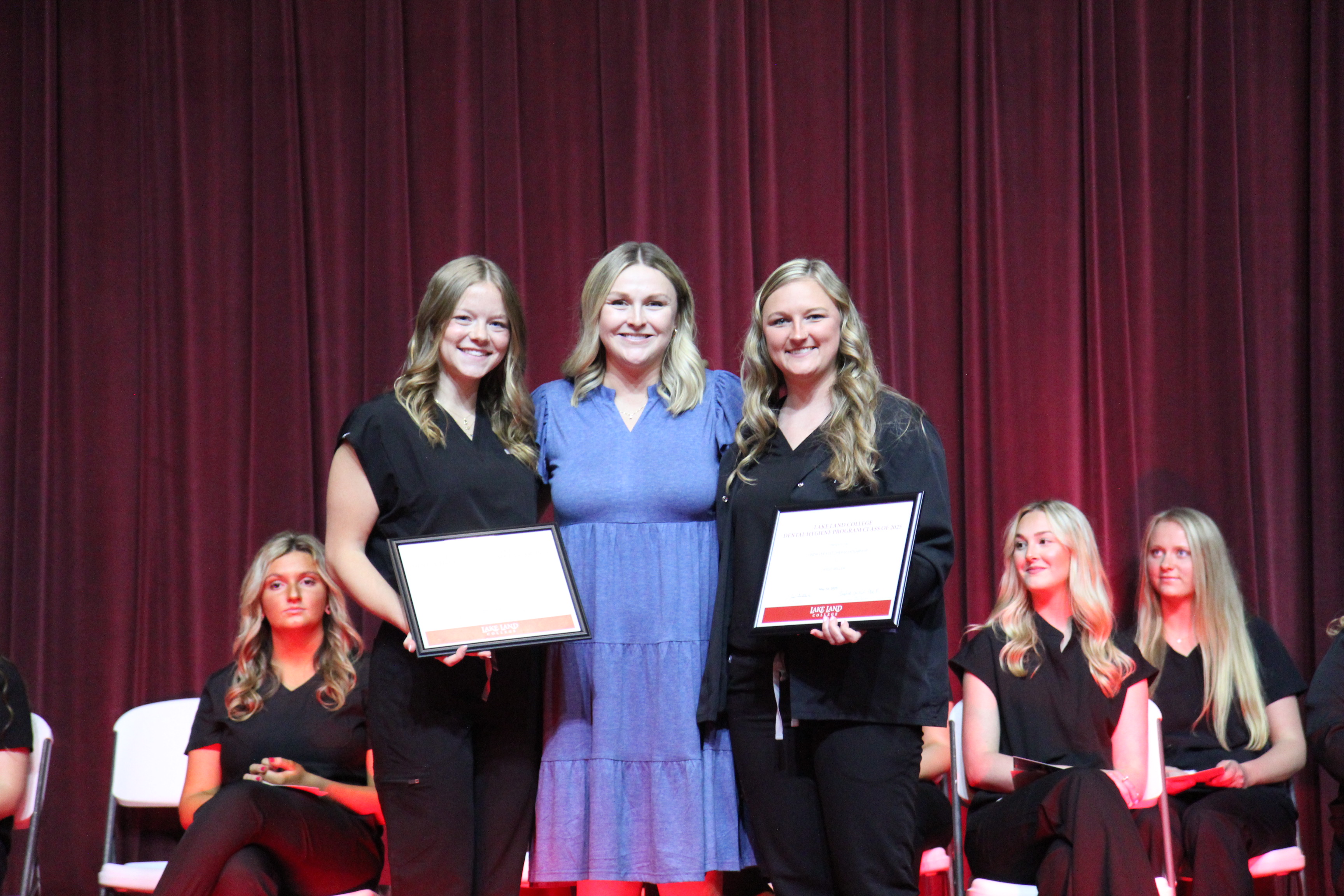 Two Lake Land College Dental Hygiene students receiving a scholarship award during a graduation ceremony. 