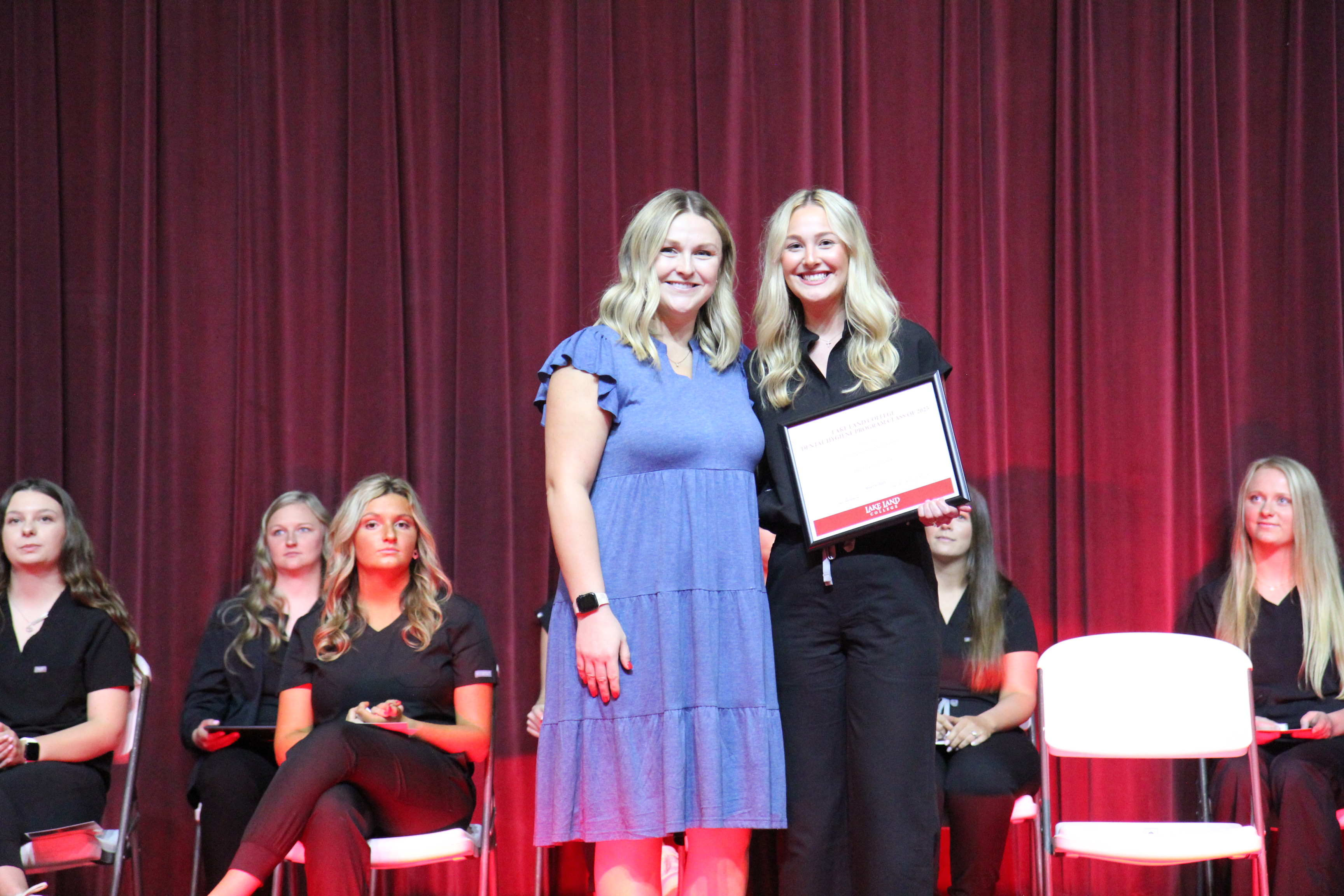 A Lake Land College Dental Hygiene instructor presenting an award to a graduating student during a ceremony. 