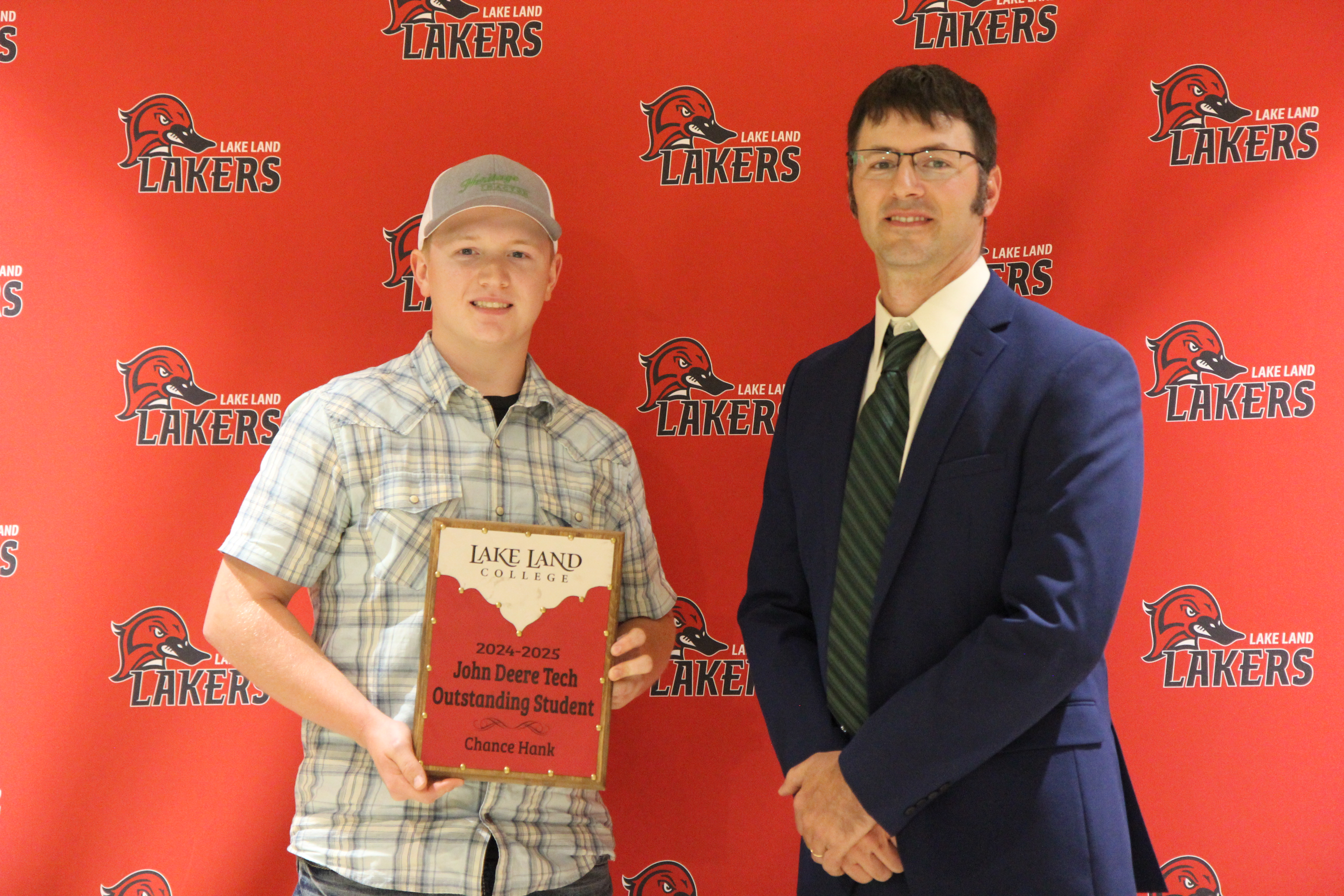A Lake Land College John Deere Tech instructor presenting an award to a graduating student. 