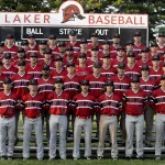 Baseball players posing for a picture standing on bleachers on a baseball field