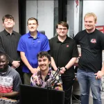 Students posing for a photo in a broadcasting studio