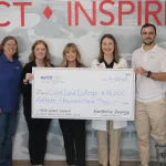 People posing for a photo holding a big check