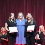 Students posing for a photo holding an award