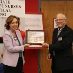 Man and woman posing for a photo and holding an award together