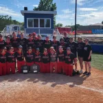 Softball players posing for a photo on a softball field