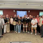 Photo of Dr. Bullock with student athletes at a Board of Trustees meeting