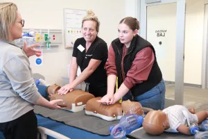 An image of Simulation Lab Nurse Rachael Walker and Division Chair Allied Health/Nursing Instructor Erin Swingler leading a CPR demonstration along with a high school student volunteer to help students learn about careers in healthcare during the College’s first-ever Laker Day at the new Effingham Technology Center. 