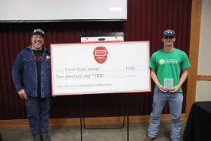 An image of Lake Land College Welding Instructor/Program Coordinator James Crowder presenting the 1st Place Senior award to Brayden Nickle, South Vermillion High School, during the first-ever Laker Connect Dual Credit High School Welding Competition.