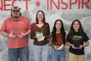 The four Lake Land College 2026 Distinguished PTK Officers standing together with their plaques. 