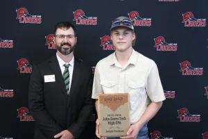 An instructor presenting the 2025-2026 John Deere Tech High GPA Award to a student during the annual Lake Land College John Deere Tech graduation ceremony. 