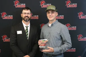 An instructor presenting the 2025-2026 Most Improved Student Award to a student during the annual Lake Land College John Deere Tech graduation ceremony. 