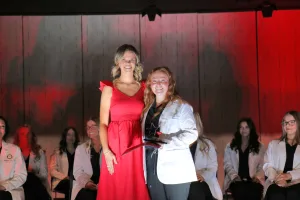 A dental hygiene graduate receiving an award from an instructor during a graduation ceremony.