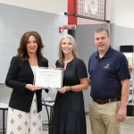 Two workforce experts presenting a certificate to an individual who recently completed a registered apprenticeship.