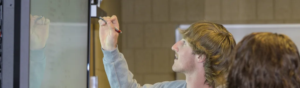 a photograph of a student working at a smart board.