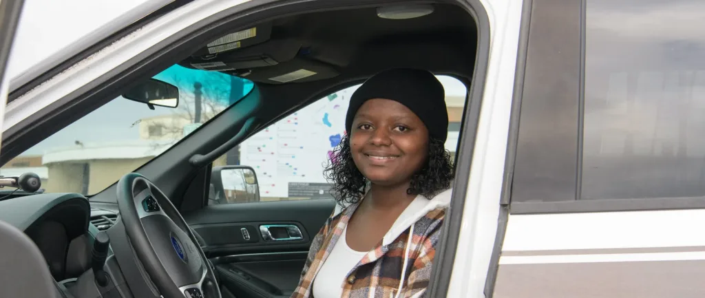A photograph of a criminal justice student in a cop car.