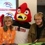 Lake Land College mascot dressed up for Halloween and posing for a photo with two students.