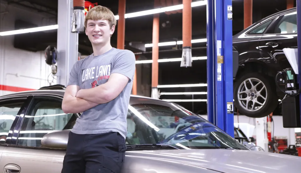 An automotive student standing by a car.