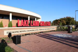 Lake Land College's Sullivan Plaza, featuring the Lake Land College name in prominent red lettering and the College's mission statement engraved in a brick half wall. On the ground in front of the wall, is a brick platform featuring the College's official seal.